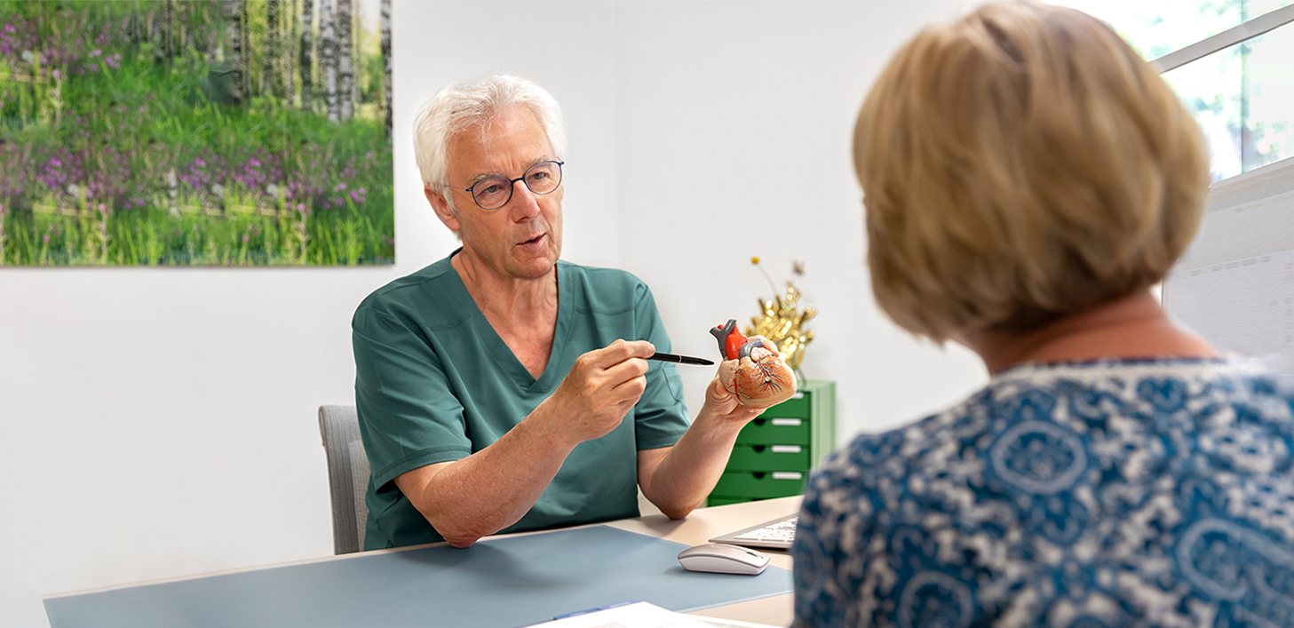 MVZ Herz Gifhorn | Therapie Ein Azrt erklärt etwas einer Patientin mittels eines Modellherzens.